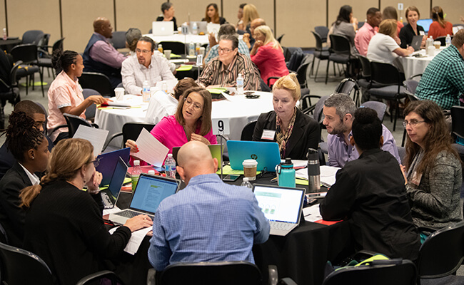 Symposium attendees in discussion at round tables.