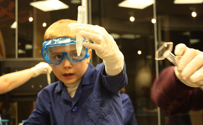 Child looking into test tube while holding it up to the light.
